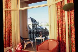 Cette chambre dispose d'une grande fenêtre avec une table et des chaises. dans l'établissement Hôtel Aletti Palace, à Vichy