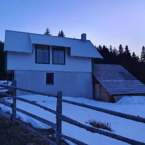 a white house with a fence in the snow at Planinska koliba Ajdanovici Jelovac Nisicka visoravan in Olovo