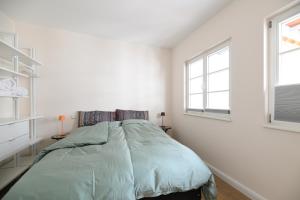 a white bedroom with a bed and two windows at Das schiefe Haus Wohnung Festspiele in Heppenheim an der Bergstrasse