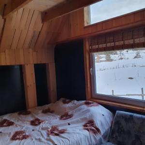 Bett in einem Zimmer mit einem Fenster mit Schnee in der Unterkunft Planinska koliba Ajdanovici Jelovac Nisicka visoravan in Olovo