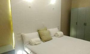 a white bed with three pillows on top of it at Brown Gate House in Panabo