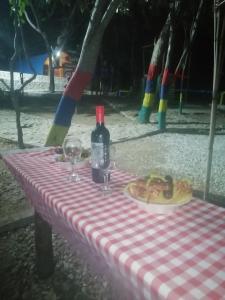a picnic table with a bottle of wine and a plate of food at tayrona breeze in Santa Marta