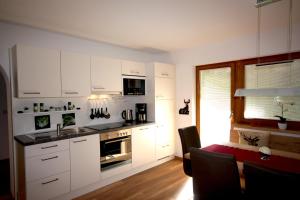 a kitchen with white cabinets and a table and a dining room at Hirschstube in Ischgl