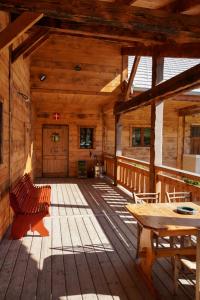 une grande véranda en bois avec une table et des bancs en bois dans l'établissement La Ferme De L'âne Rouge 7 nuits minimum, à Bernex