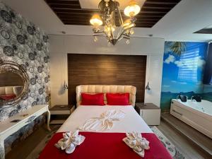 Un dormitorio con una cama grande con almohadas rojas y una lámpara de araña. en Hotel St.Pauli, en Shkodër