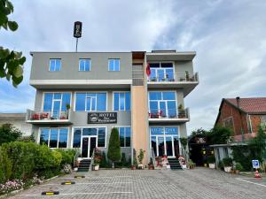 een groot gebouw met blauwe ramen aan een straat bij Hotel St.Pauli in Shkodër