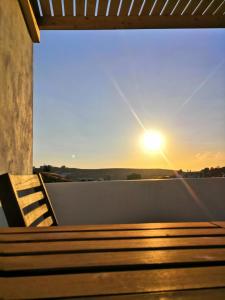 a bench on a balcony with the sunset in the background at Haroto Suites in Tripití