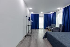 a bedroom with blue curtains and a bed and a chair at House at the Sea in Batumi