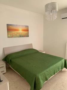 Un dormitorio con una cama verde y una lámpara de araña. en CASA VACANZE RE DEL MARE en Taranto