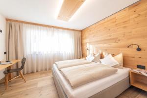 a bedroom with a large bed with a wooden wall at Ciasa Nene Franzl in Badia