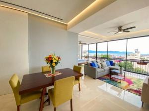 a living room with a wooden table and yellow chairs at Luxury Oceanview Modern Condo in Puerto Vallarta
