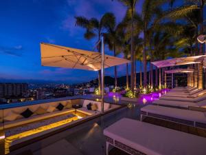 un bar en la azotea con tumbonas y palmeras por la noche en Luxury Oceanview Modern Condo, en Puerto Vallarta