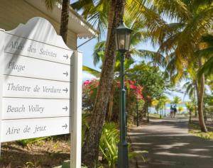 a street sign next to a street light with palm trees at Studio vue sur mer en résidence de vacances in Sainte-Anne +1 photo