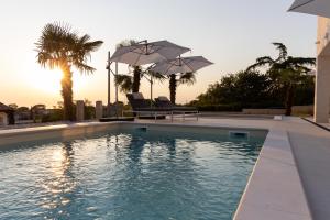 a swimming pool with two chairs and umbrellas at Sunshinewilla com - amazing sea view - private pool - 4 bedrooms - 3 bathrooms - workout in Kaštelir