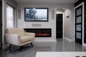 a living room with a chair and a fireplace at Stunning exec spa retreat w/panoramic lake views! in Haslett