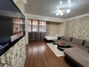 een woonkamer met een bank en een flatscreen-tv bij Къща за гости Шарон in Petrich