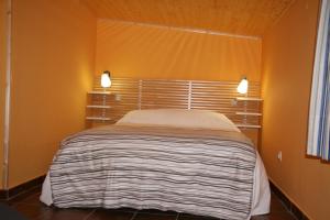 a bed in a room with orange walls and two lights at Casa Tenerías in Marchagaz