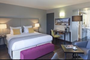 um quarto de hotel com uma cama grande e um banco rosa em Hotel de L'Universite em Paris