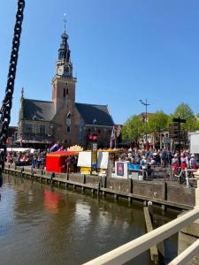 a crowd of people standing around a river with a clock tower at Mini Apartment 30 m2 with in the hart of Alkmaar in Alkmaar