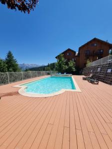 una gran piscina en una terraza de madera en APPARTEMENT T2 30m2 VUE EXCEPTIONNELLE PUY SAINT VINCENT AVEC PISCINE L'ETE en Puy-Saint-Vincent