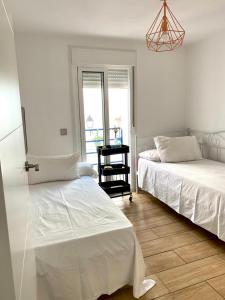 a bedroom with two beds and a chandelier at La casita de Lú in Casares