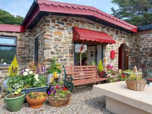 a bench in front of a stone building with flowers at Bayview Lodge New Spacious Apartment in Breakish