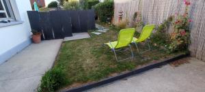two green chairs sitting in a yard next to a fence at Nid de verdure à 15 minutes centre et plage in Le Havre