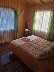 1 dormitorio con 1 cama grande y cortinas verdes en Cabañas Altos de la Chacra en Castro, 3 dormitorios, en Castro