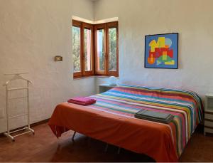een slaapkamer met een bed met een kleurrijke deken bij Kirù Lovely Home - Villa Su Cuile, Cala Ginepro in Monte Petrosu