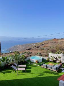 vistas a un césped con bancos y una piscina en Casa con piscina y jardín con vistas al mar, en Puerto de la Madera