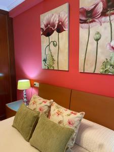 a bedroom with a red wall with a bed and two paintings at Xunqueira Playa in Moaña