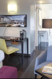 فندق دو لونيفيرسيتيه في باريس: غرفة معيشة مع طاولة وكراسي ومطبخ