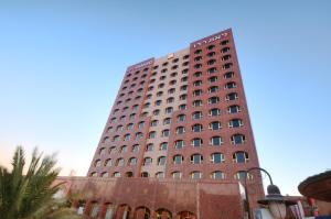 a tall red building with many windows at Leonardo Hotel Negev in Beer Sheva