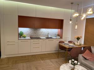 a kitchen with white cabinets and a dining table at CRYSTAL CAVE Apartment in Wieliczka