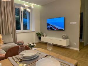 ein Wohnzimmer mit einem Tisch und einem TV an der Wand in der Unterkunft CRYSTAL CAVE Apartment in Wieliczka
