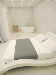 1 dormitorio blanco con 1 cama grande y bañera en Elegant basement Suite, en Orosei