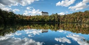 eine Reflexion eines Gebäudes im Wasser eines Sees in der Unterkunft Ferienwohnung Schloss Burgk in Burgk