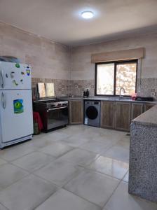 a kitchen with a white refrigerator and a window at Furnished house بيت مفروش ابو فارس in Ajloun