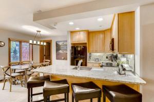 a kitchen with a large island with bar chairs at Luxury Ski In, Ski Out 3 Bedroom Mountain Residence In The Heart Of Lionshead Village With Heated Slope Side Pool And Hot Tub in Vail