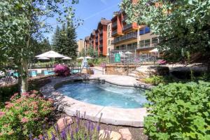 a swimming pool in a yard with a building at Luxury Ski In, Ski Out 3 Bedroom Mountain Residence In The Heart Of Lionshead Village With Heated Slope Side Pool And Hot Tub in Vail