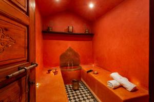 an orange bathroom with a tub and a sink at Riad Rodaina in Marrakesh