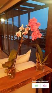 two vases with flowers in them on a table at Pousada Farol do Arvoredo in Governador Celso Ramos