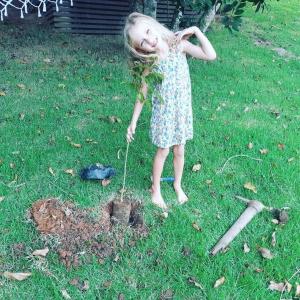 Uma menina a brincar num buraco na relva. em Pousada Farol do Arvoredo em Governador Celso Ramos