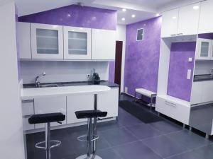 a kitchen with purple and white cabinets and bar stools at apartman Dani in Derventa