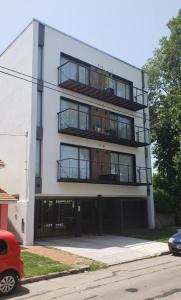 un edificio blanco con balcones y un coche estacionado frente a él en departamento San Carlos en Mar del Plata