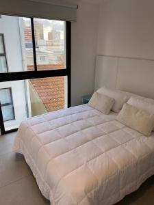 a large white bed in a room with a large window at departamento San Carlos in Mar del Plata