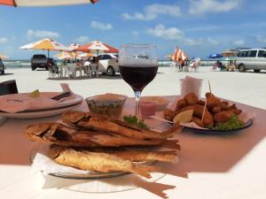a table with a plate of food and a glass of wine at Casa com piscina a 500m da praia in Salinópolis