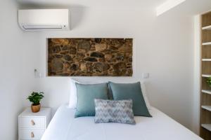 een kamer met een wit bed en een stenen muur bij Casa dos Copos - Drinks House in Miranda do Corvo