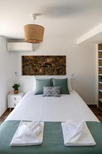 a large white bed with two white towels on it at Casa dos Copos - Drinks House in Miranda do Corvo