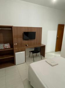 a bedroom with a bed and a tv and a desk at Prime Hotel Hortolândia in Hortolândia